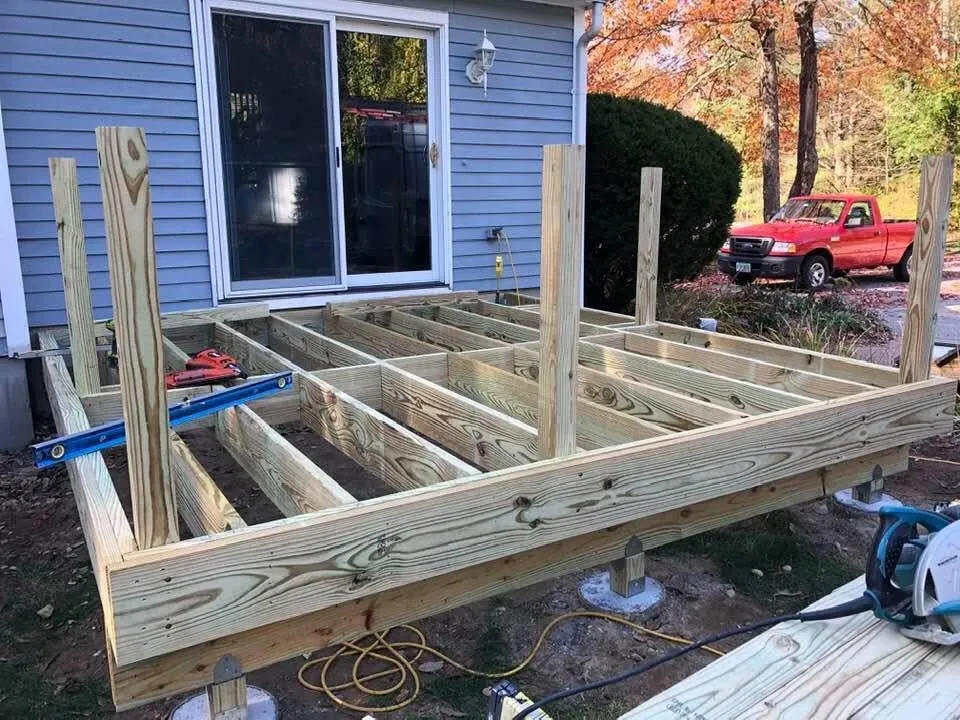 New pressure-treated deck framing against a blue house