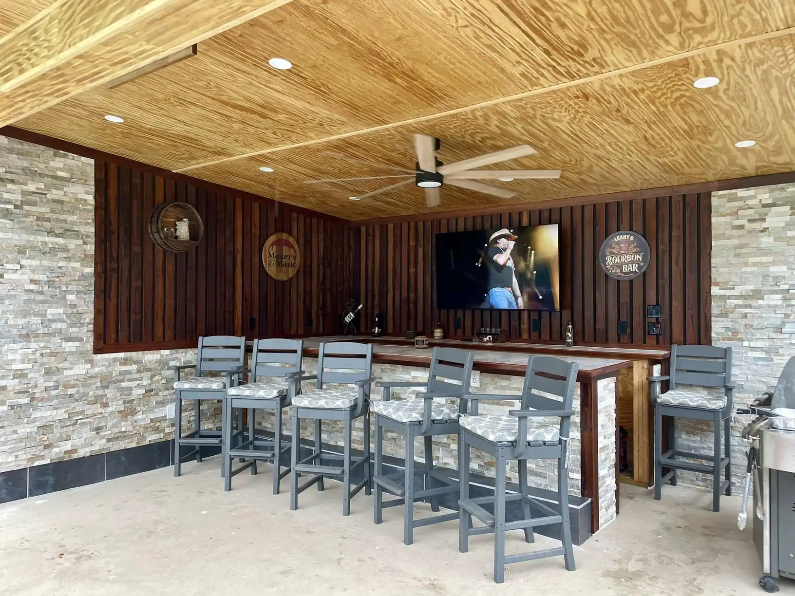 Finished bar room with a pine plank ceiling, stacked stone walls and a built-in bar