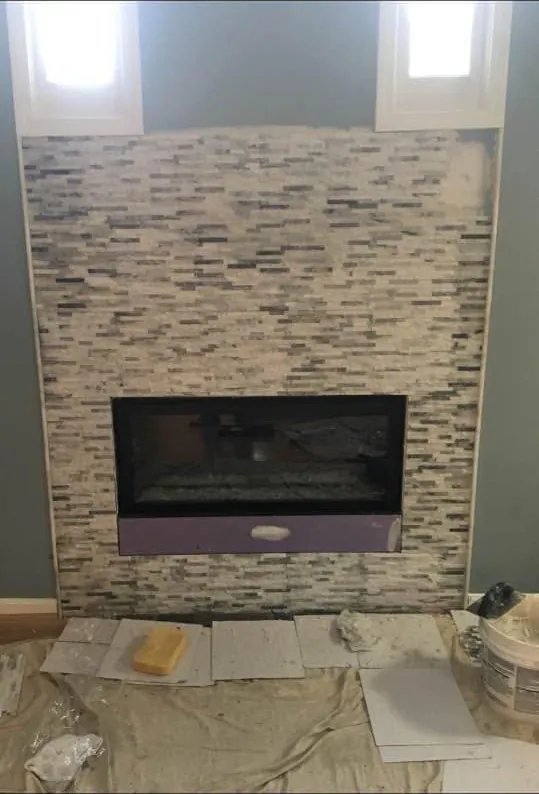 Linear fireplace with a stacked stone tile surround