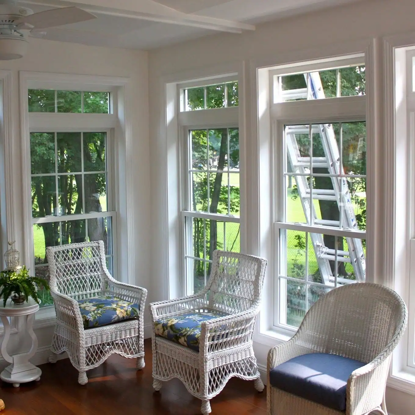 Bright sunroom with tall windows and wicker chairs